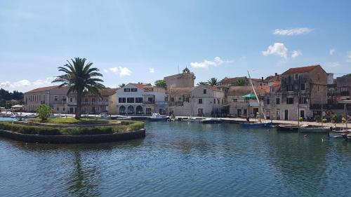 a river with boats in a city with buildings at Apartments Jerko in Vrboska