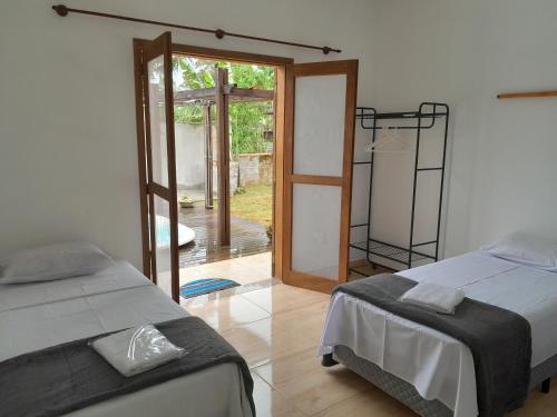 a bedroom with two beds and a door to a yard at Rancho Calamaris in Cananéia