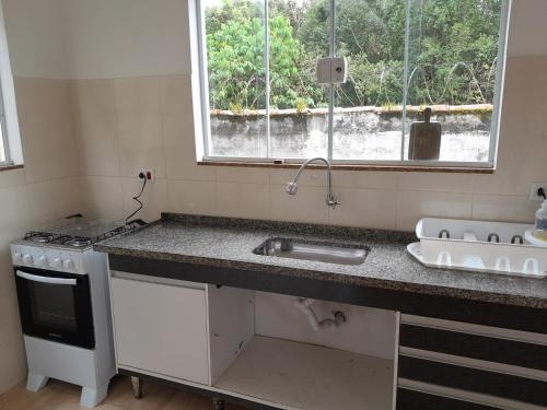 a kitchen with a sink and a stove and a window at Rancho Calamaris in Cananéia
