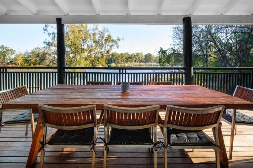 a large wooden table on a deck with chairs at Brisbane River Cabin in Mount Ommaney