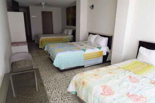 una habitación de hotel con 3 camas y una silla en HOTEL LLANITO AGS, en Aguascalientes