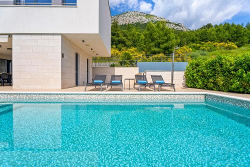 a swimming pool with chairs and a house at Villa Ivan in Omiš