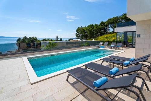 a swimming pool with chaise lounge chairs next to a house at Villa Ivan in Omiš