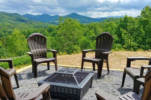 a group of chairs sitting on a patio with a fire pit at Peace of Heaven ~ Modern Chic Cabin w/ Majestic Mountain Views in Bryson City
