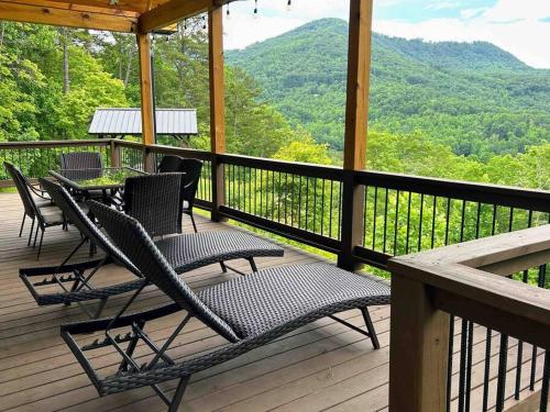 a deck with chairs and a table and a view of the mountains at Peace of Heaven ~ Modern Chic Cabin w/ Majestic Mountain Views in Bryson City