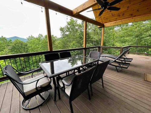 a patio with a table and chairs on a deck at Peace of Heaven ~ Modern Chic Cabin w/ Majestic Mountain Views in Bryson City