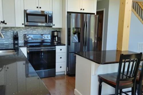 a kitchen with a stainless steel refrigerator and a microwave at Peace of Heaven ~ Modern Chic Cabin w/ Majestic Mountain Views in Bryson City