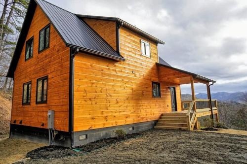 a large wooden house with a porch and stairs at Peace of Heaven ~ Modern Chic Cabin w/ Majestic Mountain Views in Bryson City