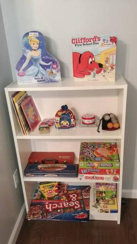 a white book shelf filled with toys and books at Peace of Heaven ~ Modern Chic Cabin w/ Majestic Mountain Views in Bryson City