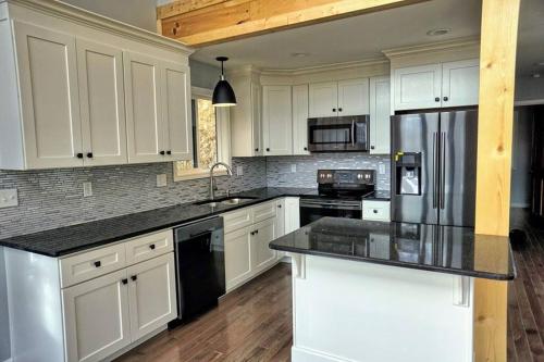 a kitchen with white cabinets and a black counter top at Peace of Heaven ~ Modern Chic Cabin w/ Majestic Mountain Views in Bryson City