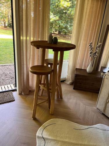 - une table et deux tabourets dans une pièce avec fenêtre dans l'établissement La perle du parc - Studio, à Rocquencourt