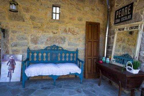 a bedroom with a blue bed in a stone wall at Eira Grande Galicia Villas in Pedre