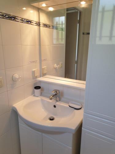 une salle de bain blanche avec un lavabo et un miroir dans l'établissement T2 classé 3 étoiles - au calme proche centre ville - idéal curistes et vacanciers, à Cambo-les-Bains