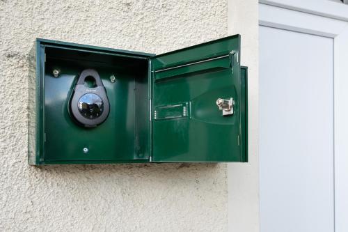 a green box on the side of a door at L'écrin des Bois - Proche aéroport Beauvais, Chantilly, forêt de Hez-Froidmont, parking public gratuit, Wifi & Netflix in Clermont