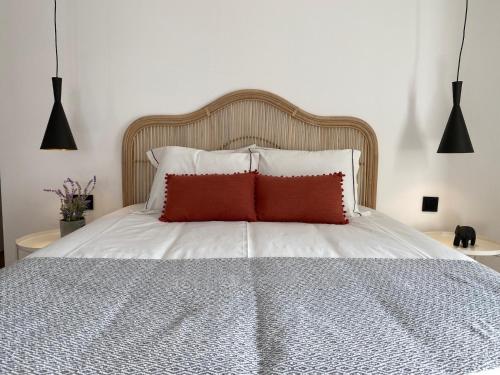 a bed with white sheets and a red pillow at Grândola Suites - Suite Afonso in Grândola
