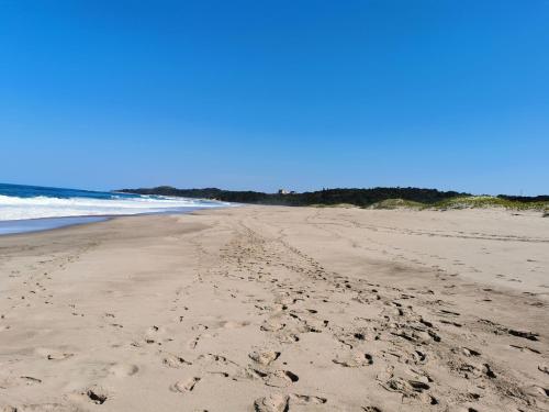 a beach with footprints in the sand and the ocean at Tortuga 22 - Caribbean Estates in Port Edward