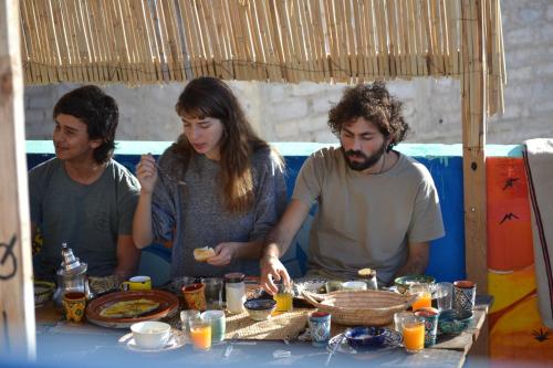 un grupo de personas de pie alrededor de una mesa con comida en sunny wave taghazout SURF & YOGA, en Taghazout