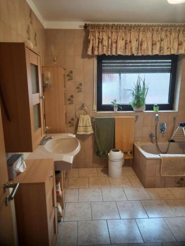 a bathroom with a sink and a tub and a window at Im Vulkanparkherz in Glees