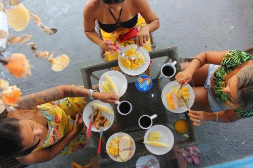 grupa kobiet siedzących przy stole jedzących jedzenie w obiekcie Casulo Hostel w mieście Porto de Galinhas