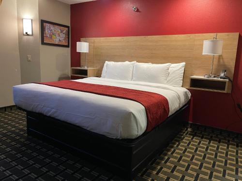 um quarto com uma cama grande e uma parede vermelha em Edn Hotel em Peoria