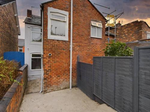 a brick house with a white door and a black fence at Cliff House By RMR Accommodations - NEW - Sleeps 8 - Modern - Parking in Stoke on Trent