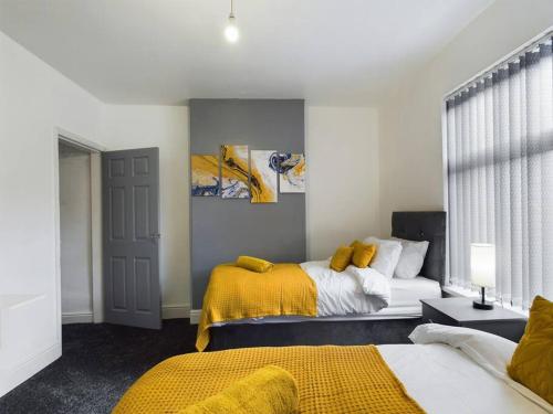 1 dormitorio con 2 camas y manta amarilla en Cliff House By RMR Accommodations - NEW - Sleeps 8 - Modern - Parking, en Stoke on Trent
