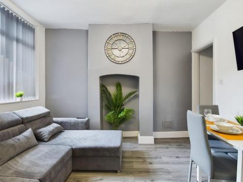 a living room with a couch and a clock on the wall at Cliff House By RMR Accommodations - NEW - Sleeps 8 - Modern - Parking in Stoke on Trent