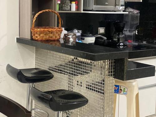 eine Küche mit einem Vogelkäfig mit zwei schwarzen Hockern in der Unterkunft Moderna Suite en Machala in Machala