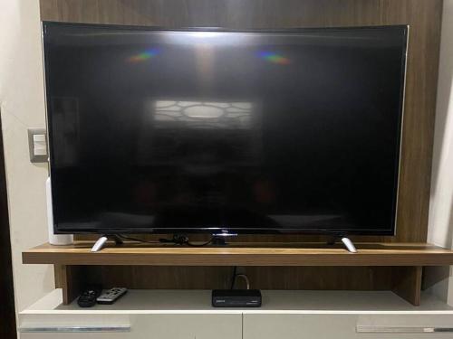 een grote flatscreen-tv zittend op een houten standaard bij Moderna Suite en Machala in Machala