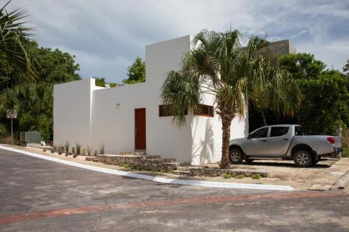 a car parked next to a white house with a palm tree at Aldea Agape in Puerto Morelos