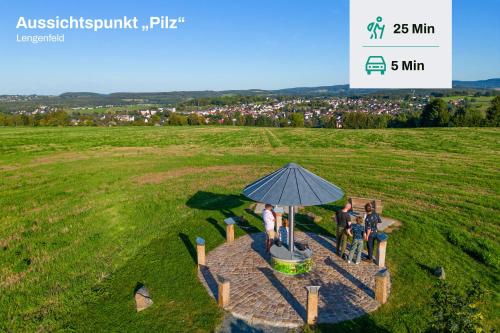 three people sitting on a bench under an umbrella in a field at Familienwohnung im Vogtland in Lengenfeld