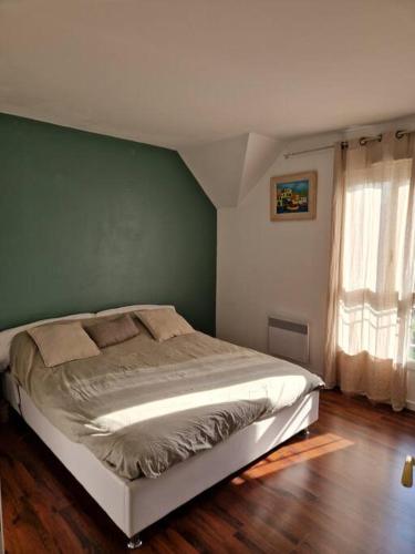 - une chambre dotée d'un lit avec un mur vert dans l'établissement Agréable Maison très proche de Tours, à La Riche