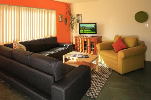 a living room with two couches and a television at Peninsula Hideaway Apartment • Alamitos Bay in Long Beach