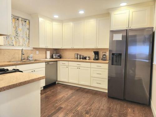 cocina con armarios blancos y nevera de acero inoxidable en Cozy contemporary 2BR with Sofa bed in the office, en Seattle