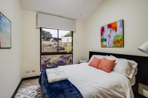 a bedroom with a large bed and a window at CR MARIPOSA RENTALS Comfortable penthouse, AC, pool, gym, tennis in Santa Ana