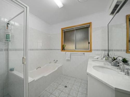 uma casa de banho com 2 lavatórios, uma banheira e um chuveiro em Views on Quicks Hill em Lavington