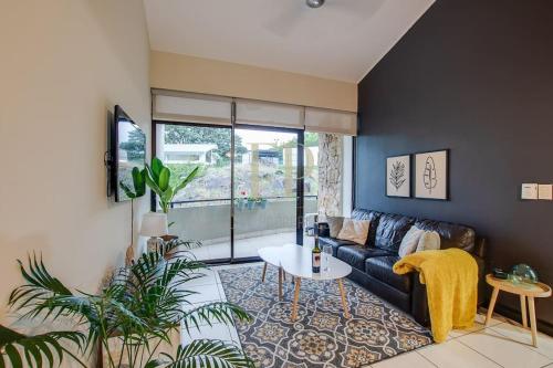a living room with a couch and a table at CR MARIPOSA RENTALS Comfortable penthouse, AC, pool, gym, tennis in Santa Ana