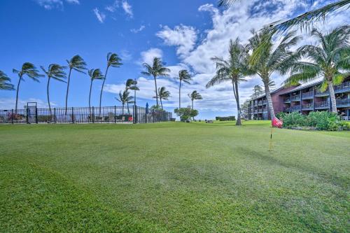 a large grassy field with palm trees in front of a building at Kaunakakai Home at Molokai Shores with Pool! in Kaunakakai
