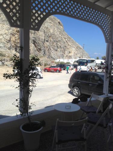 a patio with a table and a car parked in a parking lot at Sagma Beach Rooms in Perissa