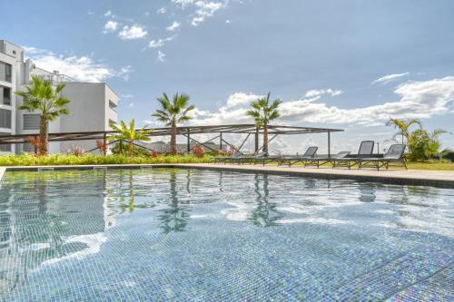 a swimming pool with two chairs and a building at Becas Place, a Home in Madeira in Funchal