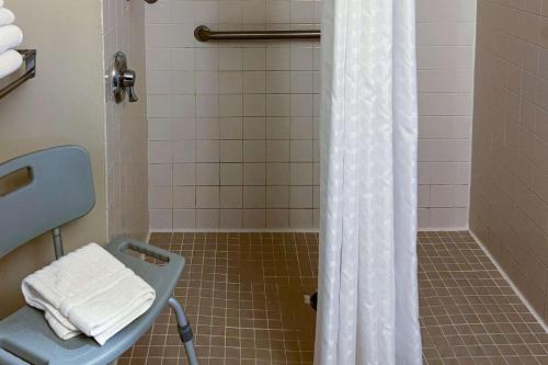 a bathroom with a shower with a chair and a shower curtain at Comfort Inn in Colville