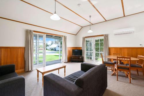 a living room with couches and a table and a television at Huka Falls Resort in Taupo