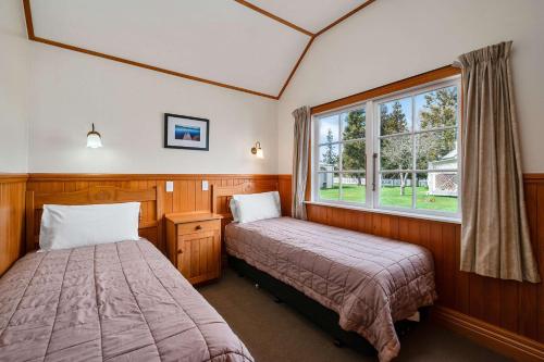 two beds in a room with a window at Quality Suites Huka Falls in Taupo