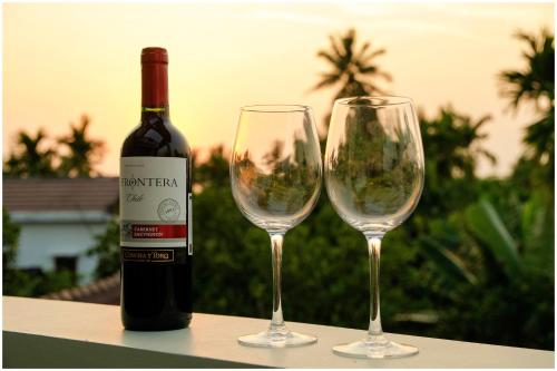 a bottle of wine and two wine glasses on a table at Goda Boutique Hotel in Hoi An