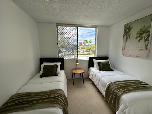 two beds in a room with a window at Meridian Tower Kirra Beach in Gold Coast