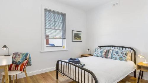 a bedroom with a bed and a window and a chair at Hobart character apartment - North View on Argyle in New Town