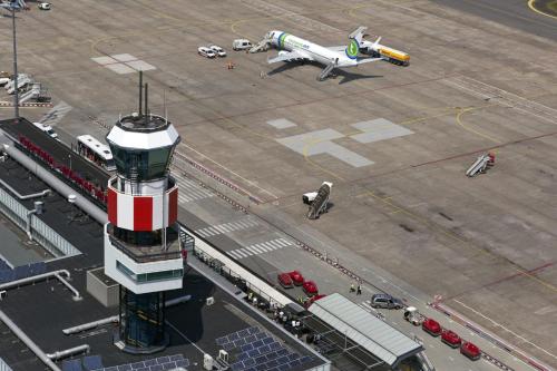 an airport control tower with a plane parked at an airport at Fletcher Hotel-Restaurant Wings-Rotterdam in Rotterdam
