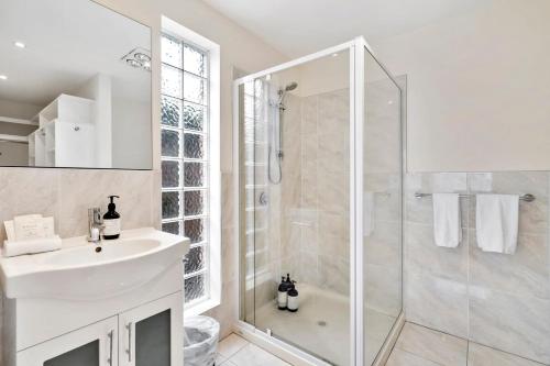 a white bathroom with a shower and a sink at Chapman Street Townhouse - walk beach & stadium in Bellerive