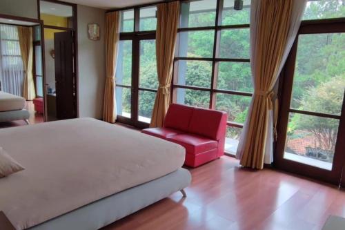 - une chambre avec un lit, une chaise rouge et de grandes fenêtres dans l'établissement Serenity on a 1740m² land, à Lembang