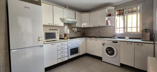 プエルトリャノにあるCasa de tres habitaciones con hermoso patioのキッチン(白いキャビネット、洗濯機、乾燥機付)